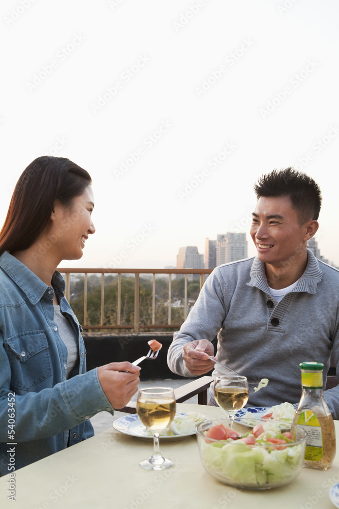 Young couple eating on the roof top