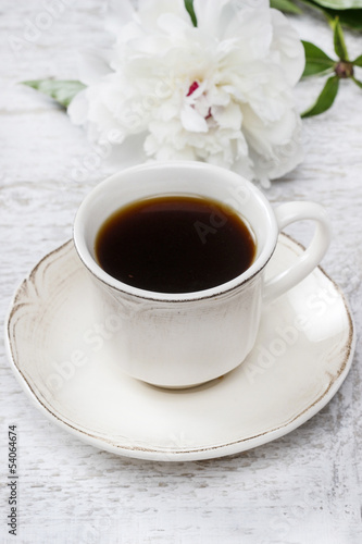 Cup of coffee and white peony on wooden rustic table