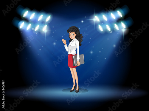 A lady holding a binder standing in the middle of the stage