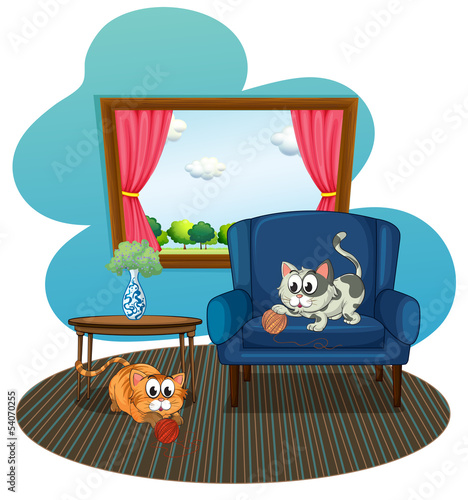 Two cats playing with the balls of yarn inside the house