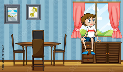 A boy sitting above the cabinet near the window