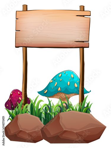 An empty wooden signboard near the big mushrooms and rocks