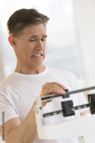 Man Clenching Teeth While Using Balance Weight Scale