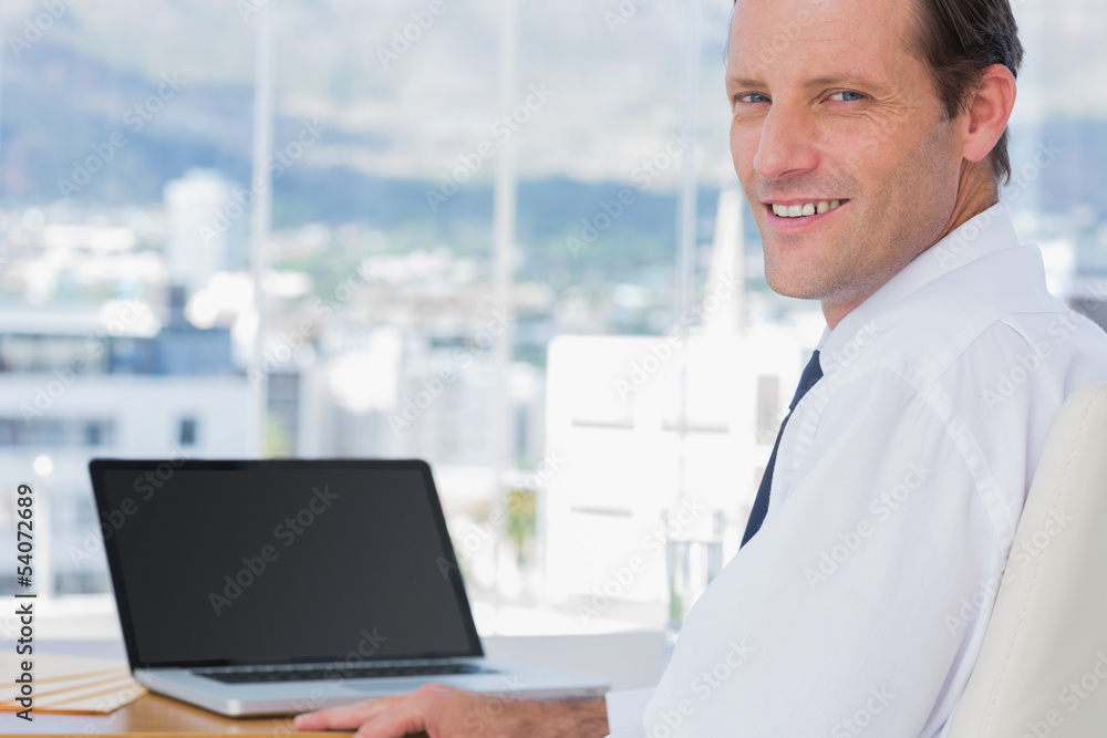Obraz premium Cheerful businessman sitting in front of a laptop