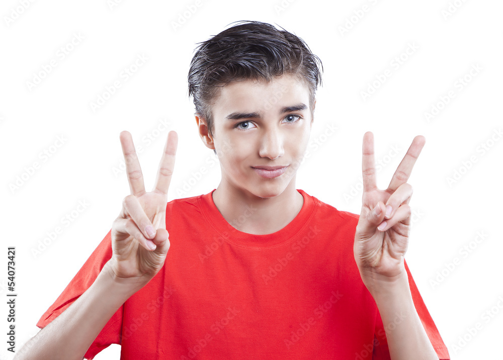 Portrait of handsome young boy showing victory sign on white bac