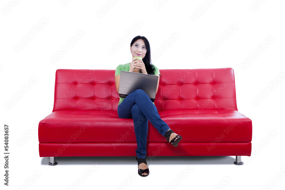 Asian female thinking on red sofa - isolated Asian female thinking on red sofa - isolated