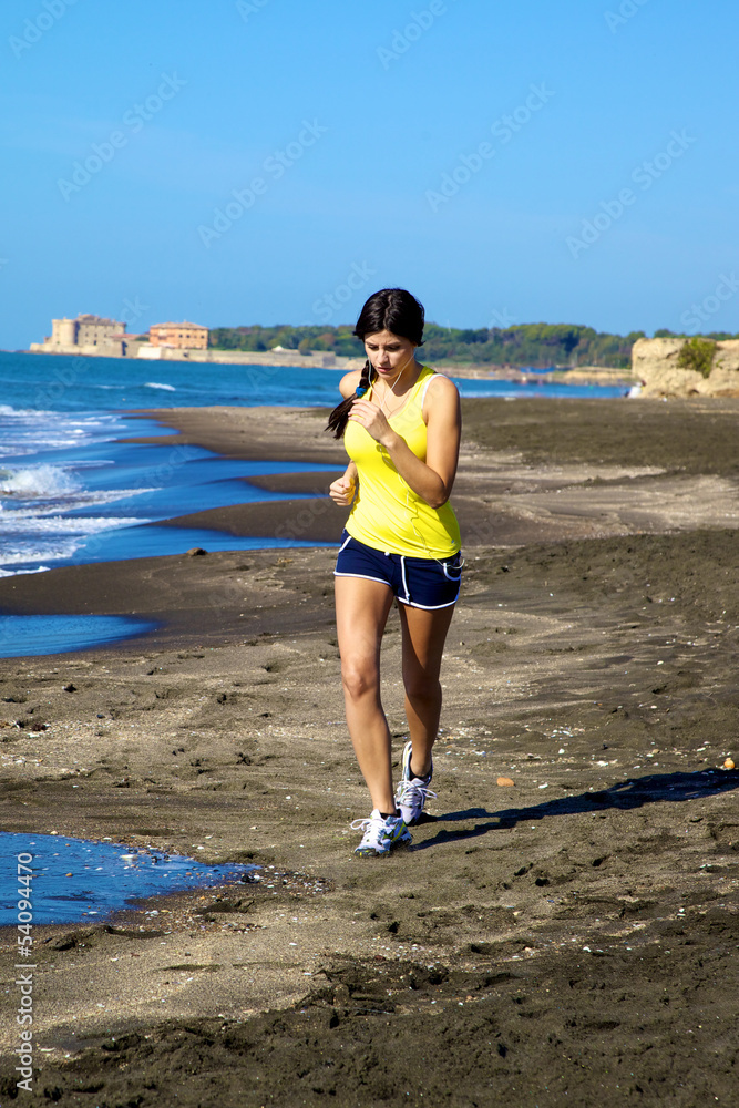 Woman jogging on the beach while listening music