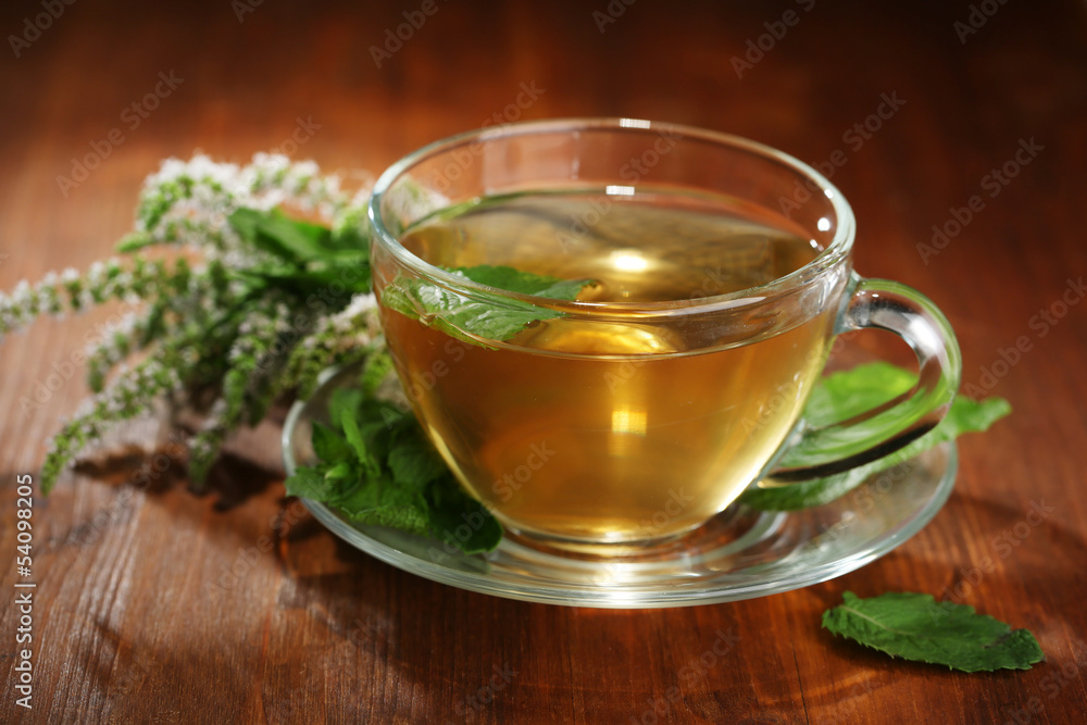 Cup of herbal tea with fresh mint flowers on wooden table Cup of herbal tea with fresh mint flowers on wooden table