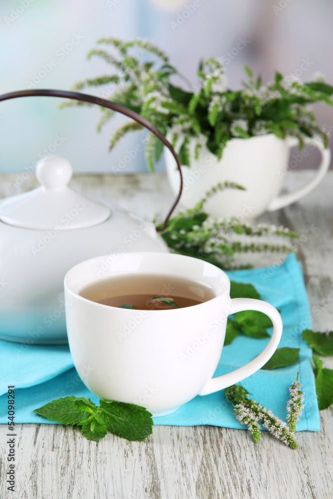 Teapot and cup of herbal tea with fresh mint flowers Teapot and cup of herbal tea with fresh mint flowers