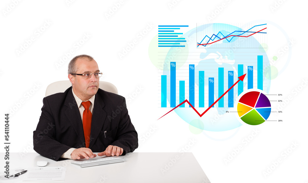 Businessman sitting at desk with statistics Businessman sitting at desk with statistics