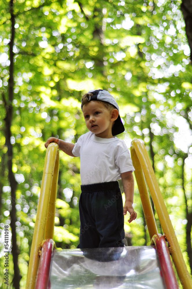 Baby climbed the hill on blurred background of trees
