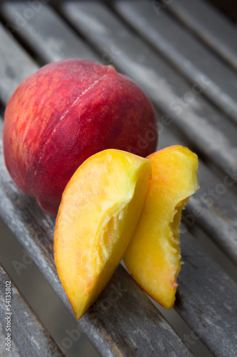 Peach with its slices on a wooden table