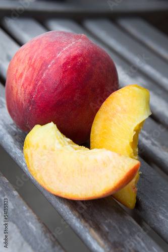 Peach with its slices on a wooden table