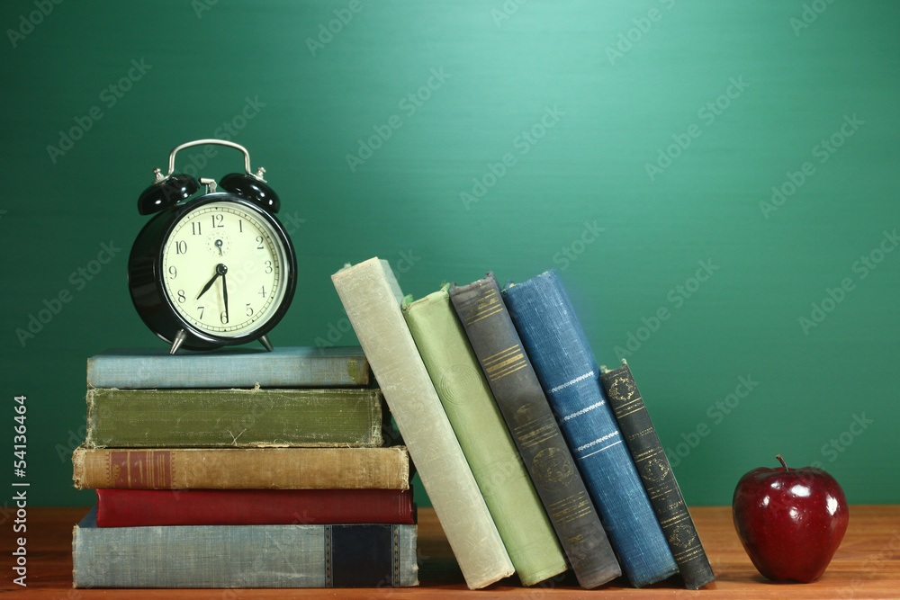School Books, Apple and Clock on Desk at School School Books, Apple and Clock on Desk at School