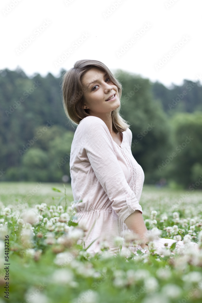 Portrait of young woman sitting on a green lawn Portrait of young woman sitting on a green lawn