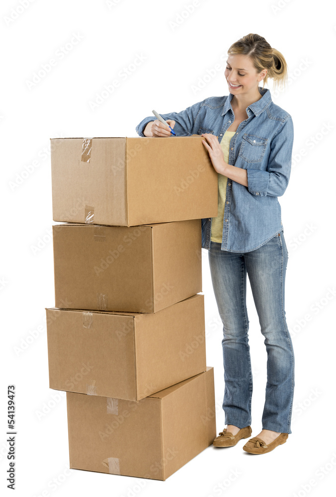 Happy Woman Writing On Stacked Cardboard Boxes Happy Woman Writing On Stacked Cardboard Boxes