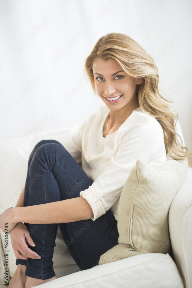 Beautiful Woman Hugging Knees While Sitting On Sofa Beautiful Woman Hugging Knees While Sitting On Sofa