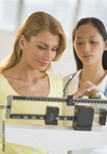 Doctor Weighing Woman On Balance Weight Scale