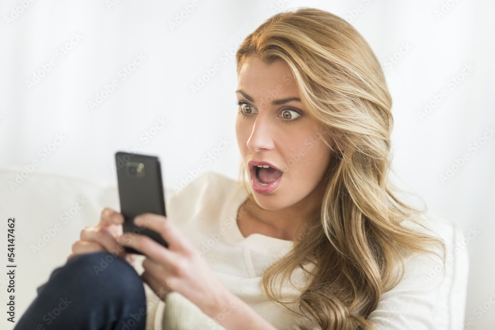 Shocked Woman Looking At Mobile Phone At Home Shocked Woman Looking At Mobile Phone At Home