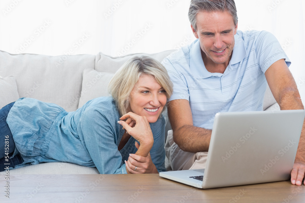 Happy couple looking at their laptop