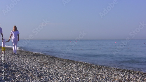 Young parents with the small child walk on the seaside