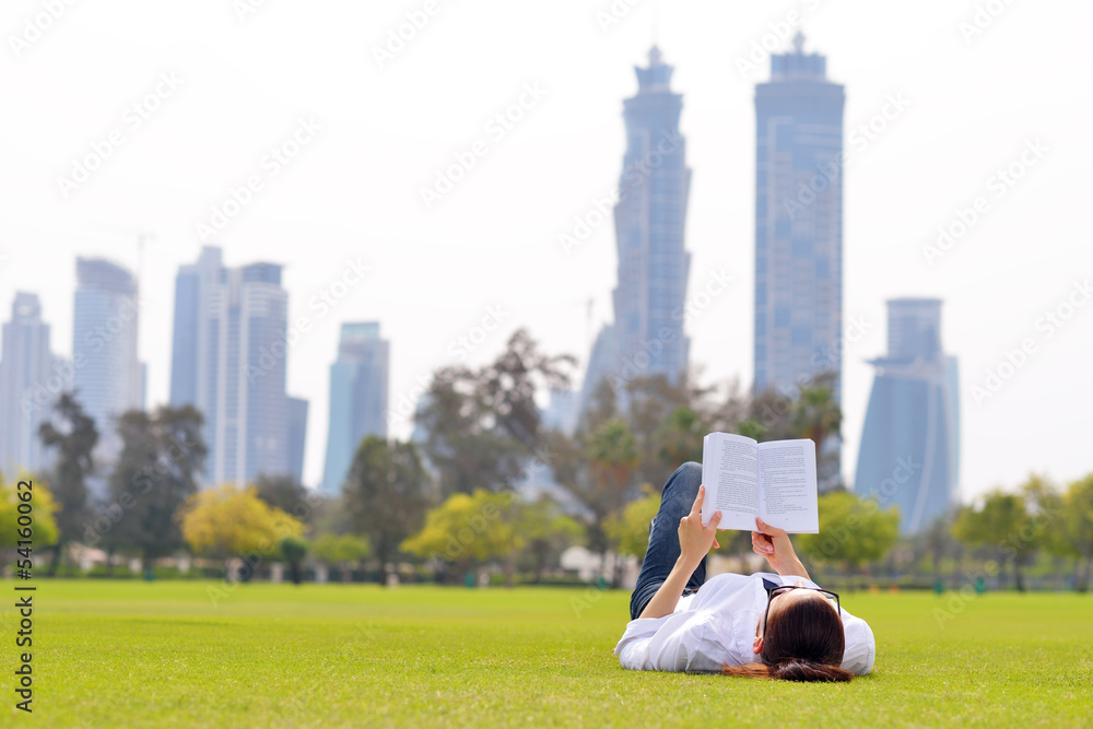 Fototapeta premium Young woman reading a book in the park