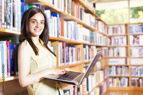 Smiling female student with laptop in a high school library