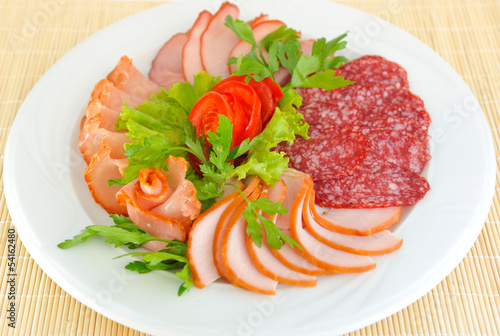 Dish with pastrami and salami slices decorated beautifully.