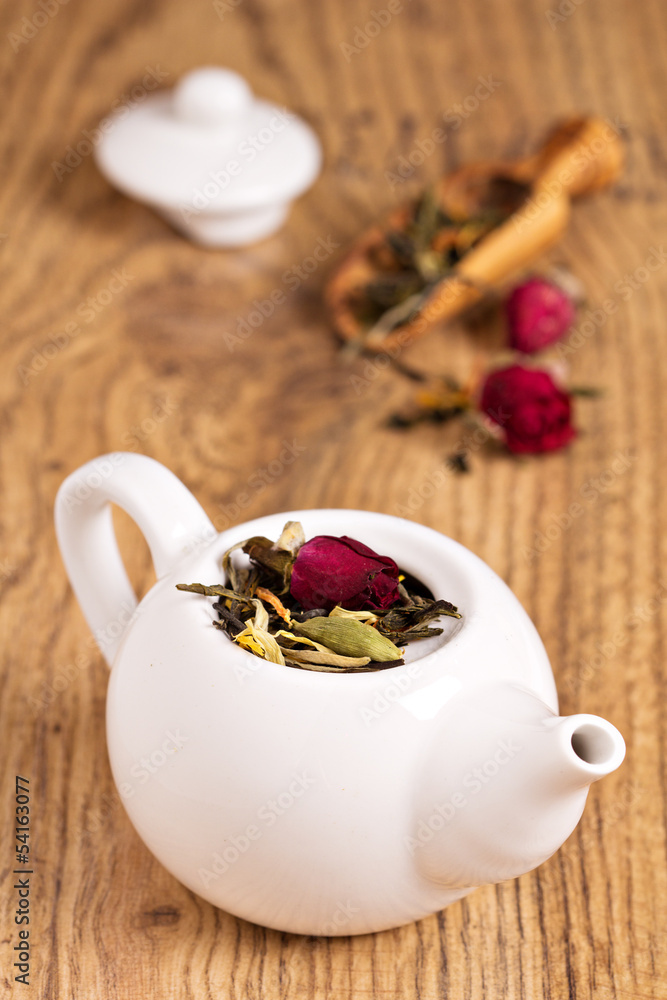 Green tea with fruits, spices, rose petals in white teapot Green tea with fruits, spices, rose petals in white teapot