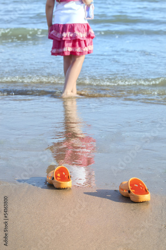 Girl's legs and slippers on the beach