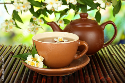 Fototapeta Naklejka Na Ścianę i Meble -  Cup of tea with jasmine, on bamboo mat, on bright background