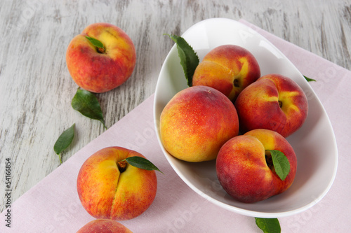Peaches in plate on napkin on wooden table