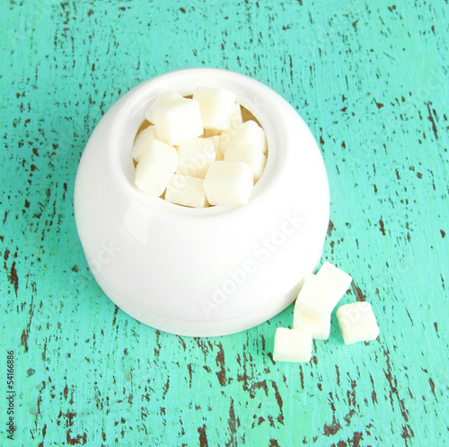 Refined sugar in white sugar bowl on wooden background photo