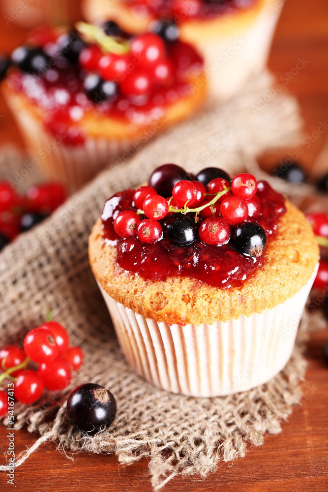 Tasty muffins with berries on wooden table