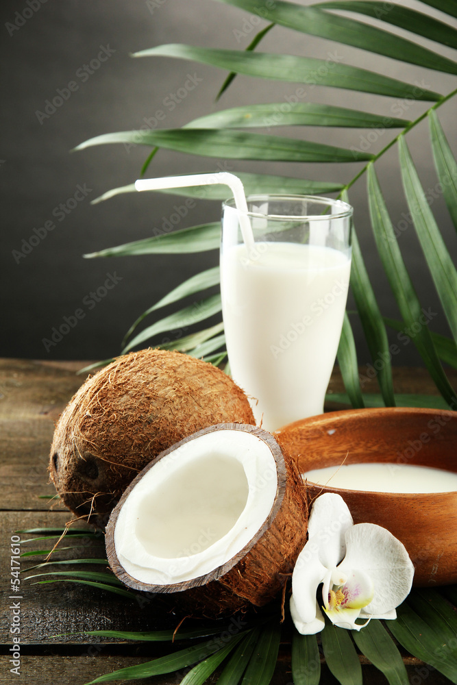 Coconut with glass of milk, on wooden table, on grey Coconut with glass of milk, on wooden table, on grey
