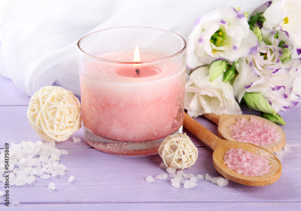 Beautiful pink candle with flowers on purple wooden background Beautiful pink candle with flowers on purple wooden background