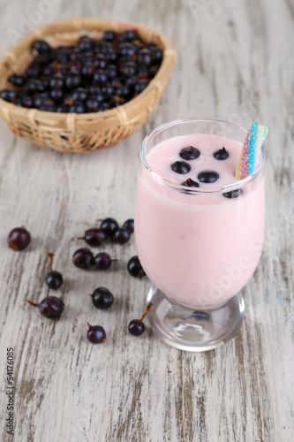 Delicious milk shake with blackberry on wooden table close-up