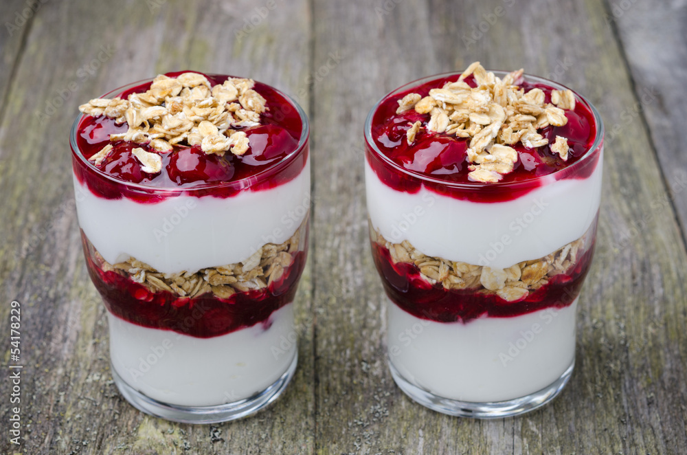 two glasses with layered dessert with yogurt, cherries, granola two glasses with layered dessert with yogurt, cherries, granola