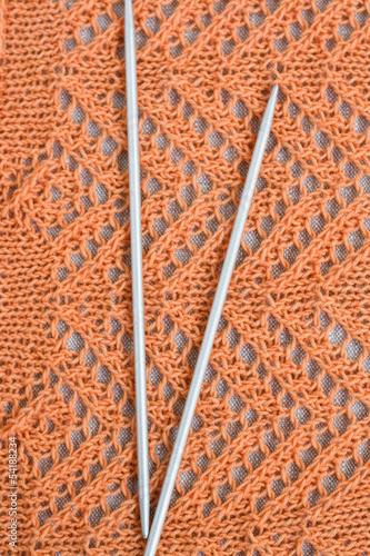 Openwork pattern with orange thread and a pair needles photo