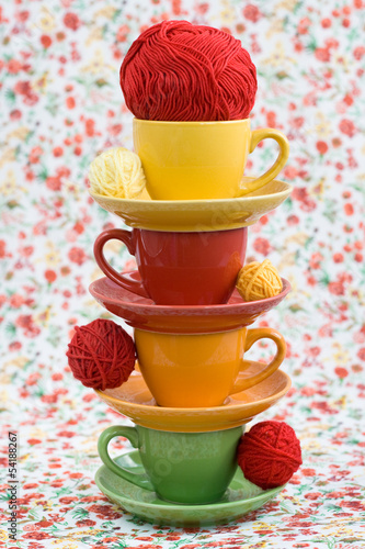 Four colorful cups and balls of yarn on a background photo