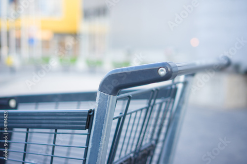 Empty grey shopping cart at supermarket entrance