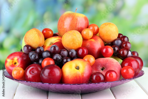 Assortment of juicy fruits on wooden table, on bright
