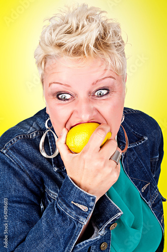 Portrait of middelaged beautiful woman eating fresh lemon photo