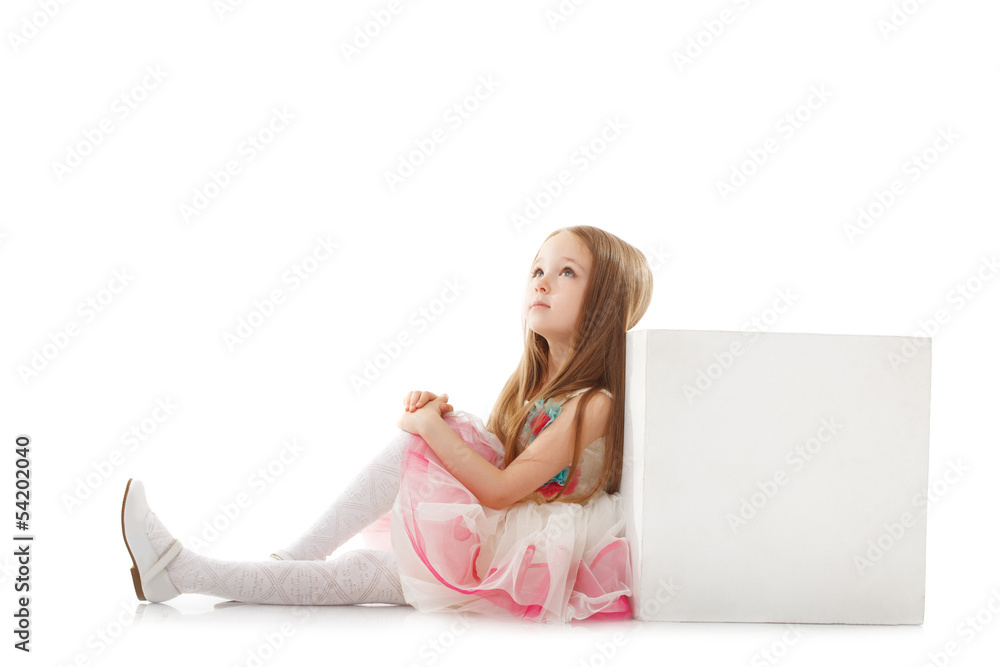 Fototapeta premium Dreamy little girl posing with cube in studio
