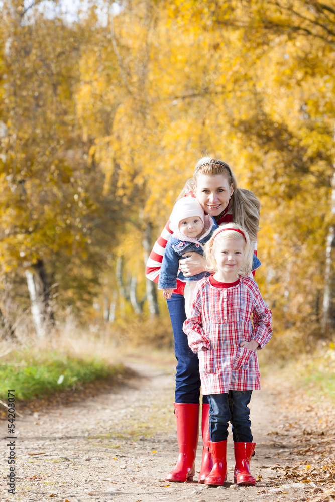 mother with her daughters in autumnal alley mother with her daughters in autumnal alley