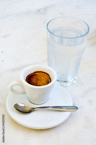 White espresso cup and glass of cold water on the marble table