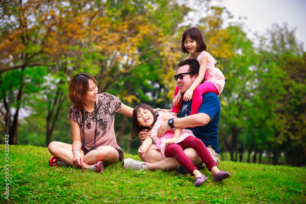 Family lying outdoors being playful and smiling Family lying outdoors being playful and smiling