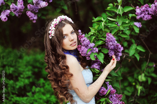 Beautiful young woman in lilac flowers, outdoors portrait