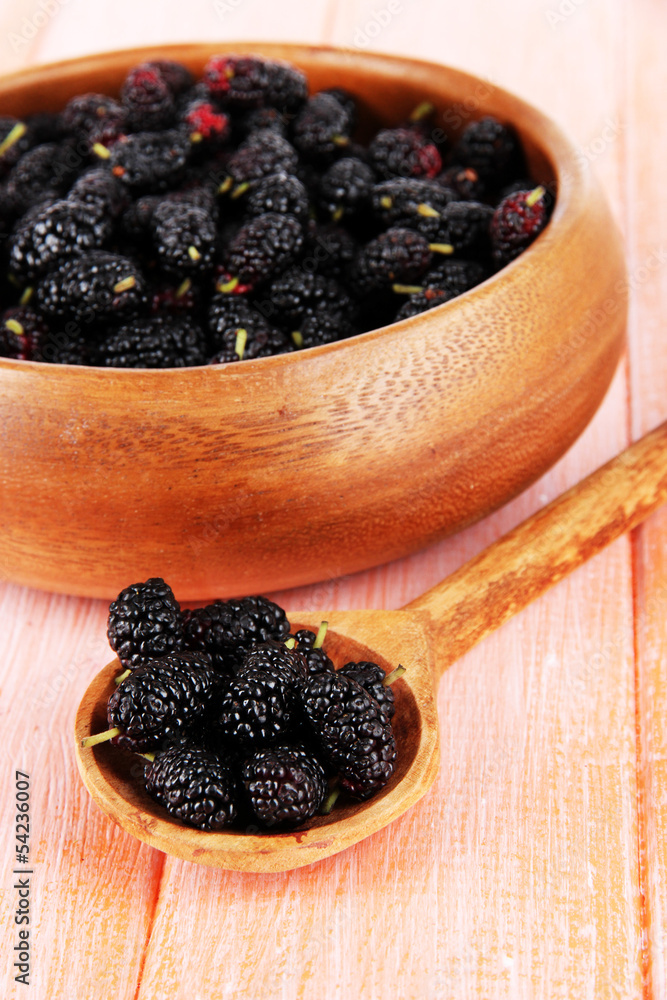 Ripe mulberries in bowl and spoon on wooden background Ripe mulberries in bowl and spoon on wooden background