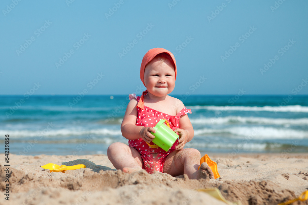 Little girl sitting on sand at beach Little girl sitting on sand at beach